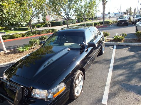 2003 Ford Crown Victoria - Black Ford sedan parked nose-out showing a black push bar, billet grille and silver wheel.