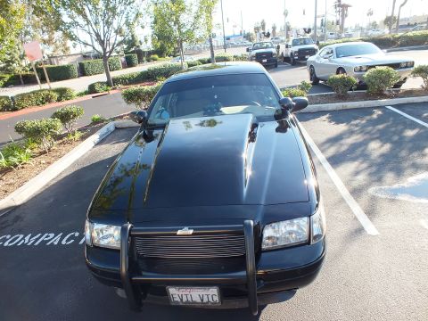 2003 Ford Crown Victoria - Head-on front view of a black Ford with push bar, billet grille and EVIL VIC California plate.