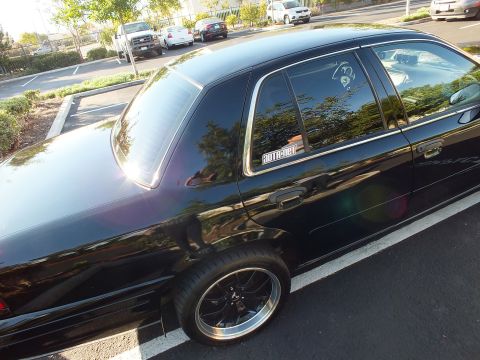 2003 Ford Crown Victoria - Black Ford sedan rear quarter with lowered stance, black machined wheels and a white window decal.