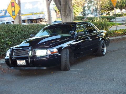 2003 Ford Crown Victoria - Black Ford sedan front quarter at curbside showing push bar, billet grille and EVIL VIC plate.