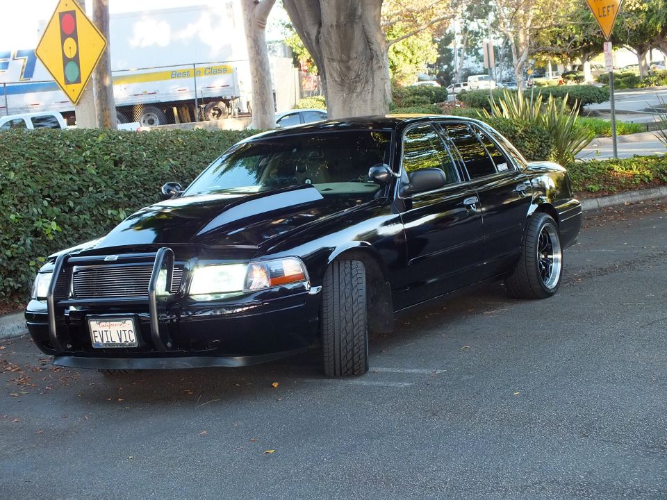 Front three-quarter of black Ford Crown Victoria with brush guard, billet grille and EVIL VIC plate