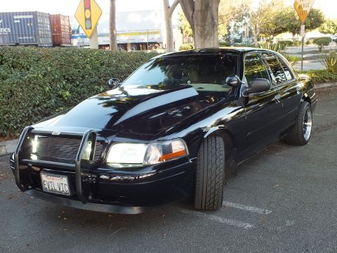 2003 Ford Crown Victoria - Black Crown Vic angled toward camera, chrome grille guard and tinted glass, plate reads EVIL VIC.