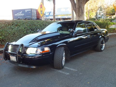 2003 Ford Crown Victoria - Glossy black Crown Vic at an angle, chrome grille guard and billet insert, EVIL VIC plate up front.