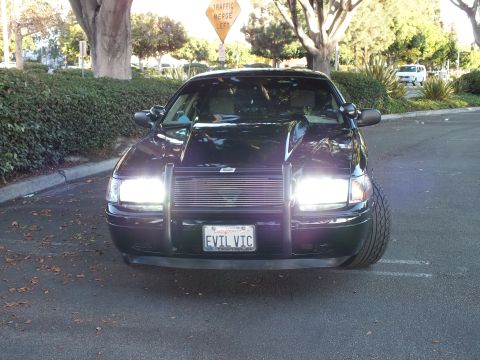 2003 Ford Crown Victoria - Head-on shot of a dark Crown Vic with headlights lit and a billet grille, front plate reads EVIL VIC.