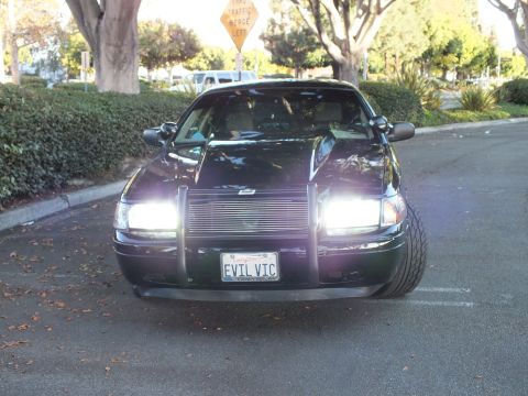 2003 Ford Crown Victoria - Frontal view of a dark Crown Vic, both headlights lit behind a billet grille, plate reads EVIL VIC.