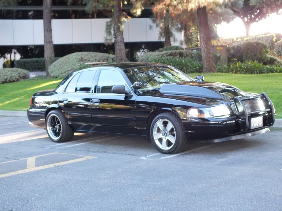 Black Ford Crown Victoria front quarter, chrome grille guard, machined wheels, office lawn behind