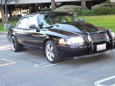 2003 Ford Crown Victoria - Black Crown Vic angled with one headlight lit, billet grille and chrome guard, EVIL VIC plate.