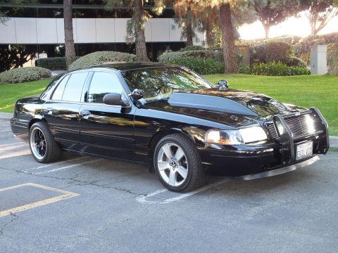 2003 Ford Crown Victoria - Black Crown Vic at an angle on machined wheels, billet grille and chrome guard, office lawn behind.