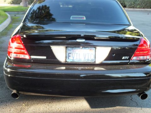 2003 Ford Crown Victoria - Close rear view of black Crown Victoria, lit taillights, EVIL VIC plate, dual black exhaust tips.