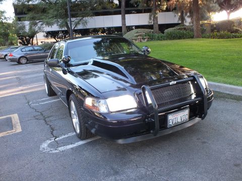 2003 Ford Crown Victoria - Front-three-quarter of black Crown Victoria, brush guard and billet grille, EVIL VIC plate, office lot.