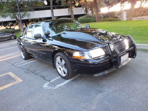 2003 Ford Crown Victoria - Front-quarter view of lowered black Crown Victoria, billet grille and brush guard, chrome wheels.