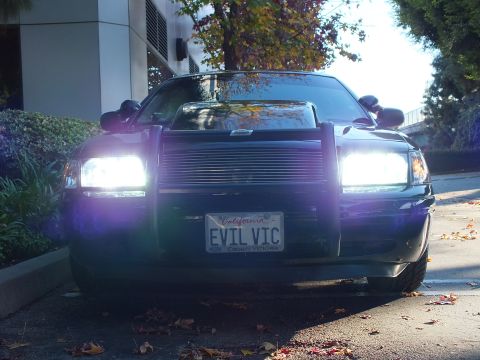2003 Ford Crown Victoria - Front view of black Crown Victoria, very bright headlights, brush guard and EVIL VIC California plate.