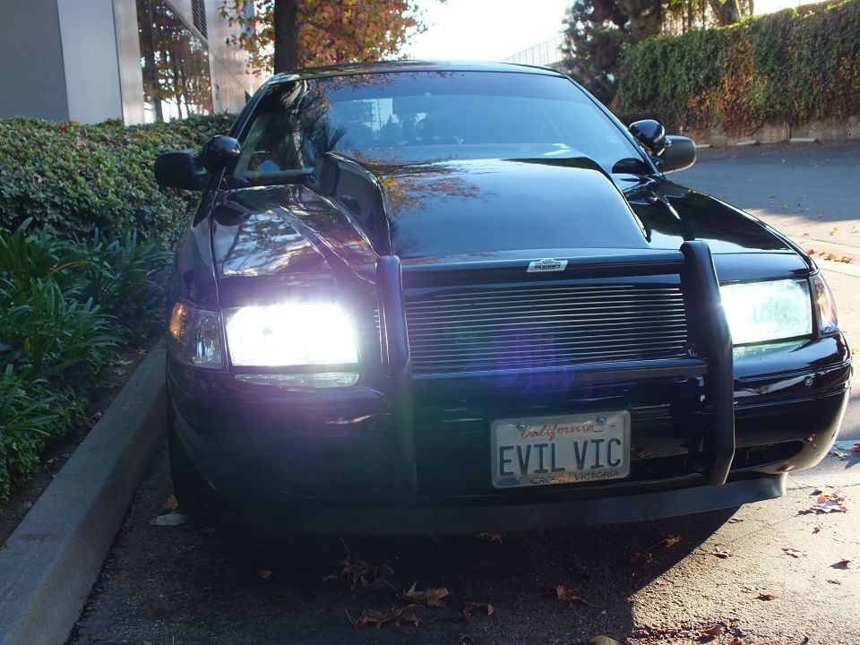 Black Crown Victoria front quarter, headlights on, billet grille and EVIL VIC California plate