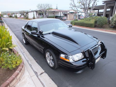 2003 Ford Crown Victoria - High front-quarter of a black sedan with grille guard and machined wheels parked in a hillside driveway.