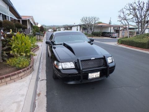 2003 Ford Crown Victoria - Front shot of a blacked-out Crown Victoria fitted with a police-style push bar parked on a residential street.