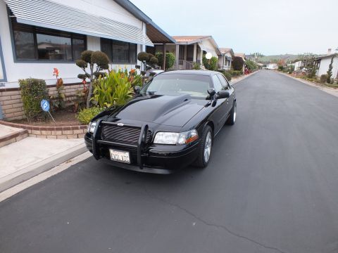 2003 Ford Crown Victoria - Front three-quarter view of a lowered black Crown Victoria with grille guard and polished wheels.