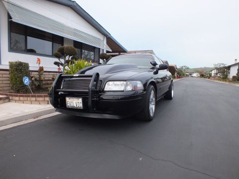 2003 Ford Crown Victoria - Close front-quarter angle of a black Crown Victoria with push bar and machined-lip alloy wheel.