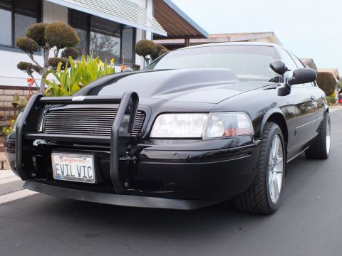 2003 Ford Crown Victoria - Tight front-corner shot showing the headlight, grille guard and Crown Victoria license plate frame.