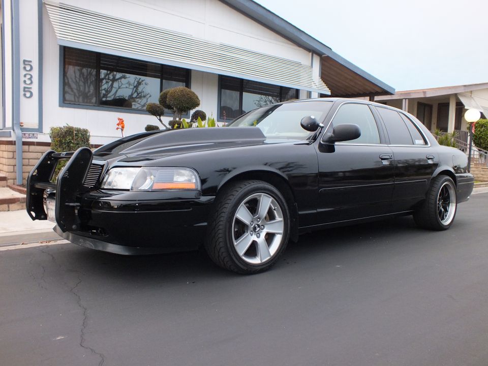 Black Crown Victoria front three-quarter parked at house number 535 with machined wheels