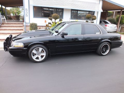 2003 Ford Crown Victoria - Side-front profile of a black Crown Victoria showing the push bar and machined-lip wheels.