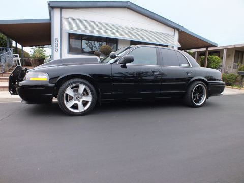 2003 Ford Crown Victoria - Driver-side profile of a lowered black Crown Victoria with grille guard at a house numbered 535.