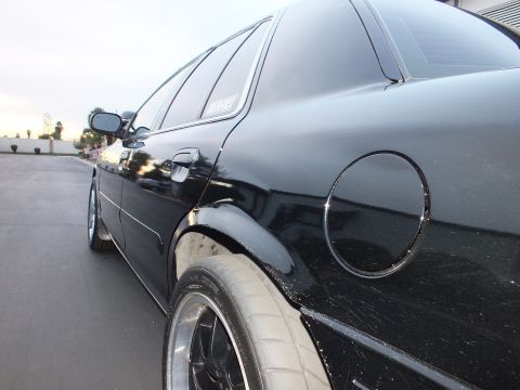 2003 Ford Crown Victoria - Low side view of a black sedan with quarter-window decal, round fuel door and polished-lip rear wheel.