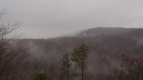 1986 Ford Bronco - A misty mountain landscape with trees in the foreground and a Supermotors logo visible.