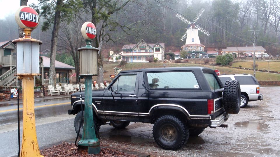 Black Ford Bronco parked next to vintage Amoco gas pumps, with a windmill and buildings in the background