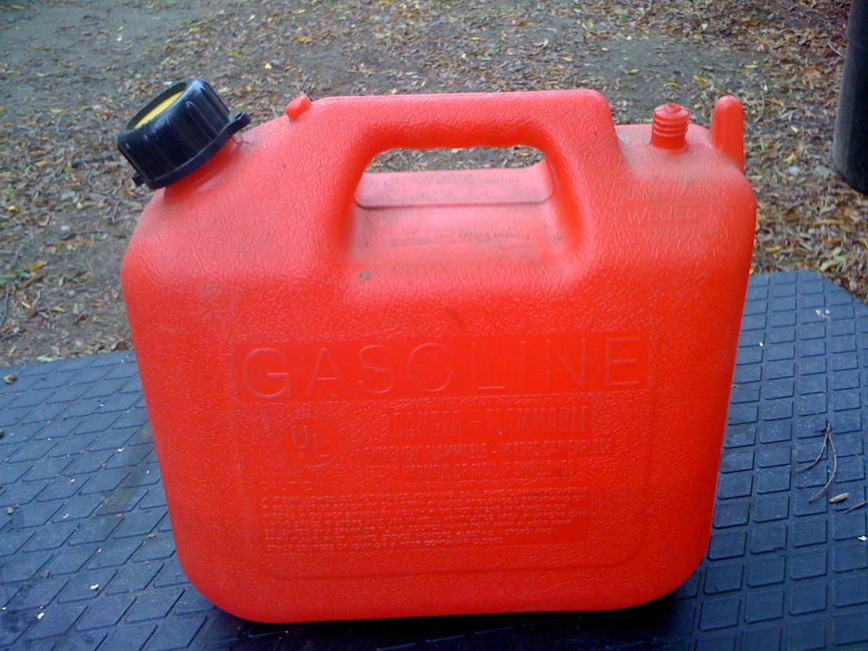 Red plastic gas can with black cap and "GASOLINE" embossed on side