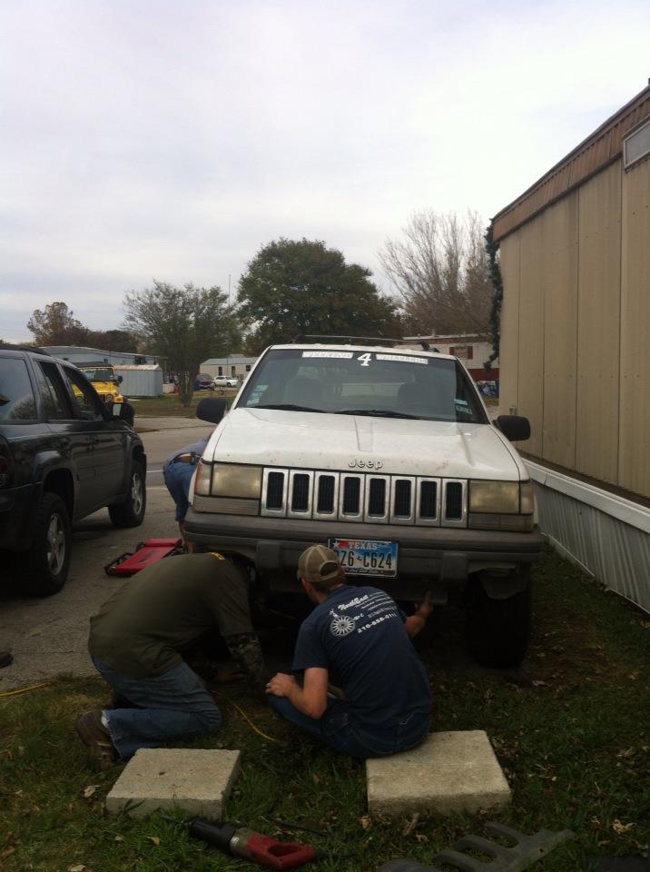 White Jeep Grand Cherokee with a license plate 26-C624, people working underneath it