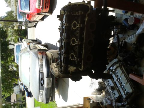 1992 Ford Taurus - Engine components are laid out on a workbench, with a dark engine block and a separate valve cover visible.