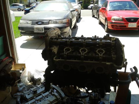 1992 Ford Taurus - Engine components are laid out for work, with other vehicles visible in the driveway.