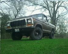 1979 Ford Bronco - Brown 1978 Ford F-150 pickup truck with aftermarket wheels sits on a grassy lawn.