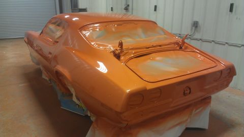 1973 Chevrolet Camaro - A muscle car in an orange primer is being worked on in a garage, with plastic covering the windows.
