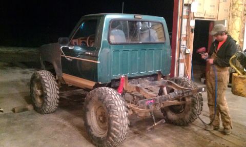 1987 Ford Bronco - A modified Ford Bronco sits in a garage, its frame and suspension clearly visible.