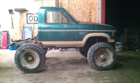 1987 Ford Bronco - A green Ford Ranger pickup truck with oversized tires and a lifted suspension is shown in a garage setting.