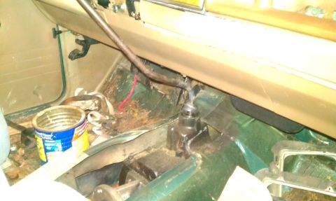 1987 Ford Bronco - Interior floor view showing rust and a shift lever; an open can is also visible.