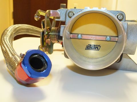 2003 Ford Crown Victoria - BBK-branded throttle body shows its open gold butterfly valve beside a braided line with blue-and-red anodized fittings.