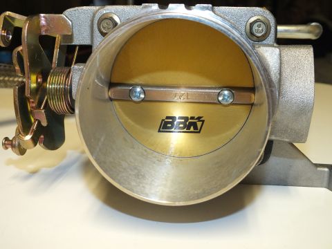 2003 Ford Crown Victoria - Head-on view of a BBK throttle body showing its open gold butterfly plate and twin screw retainers.