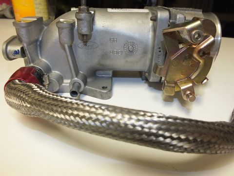 2003 Ford Crown Victoria - intake manifold with a Ford oval logo and throttle body linkage, fronted by a coiled braided line.