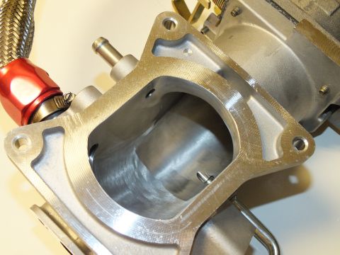 2003 Ford Crown Victoria - Macro view looking into the rectangular flange opening of a machined aluminum intake casting beside a red fitting.