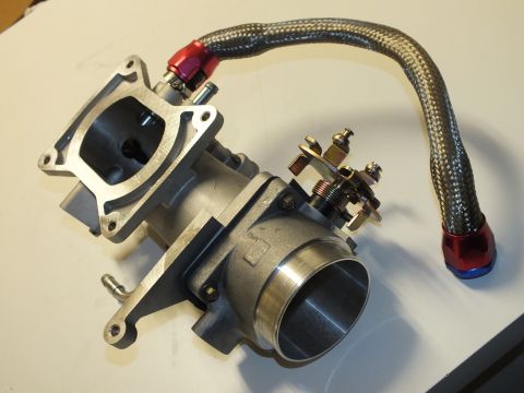 2003 Ford Crown Victoria - throttle body with an open rectangular flange, adjustment screws and a braided hose ending in red-blue fittings.