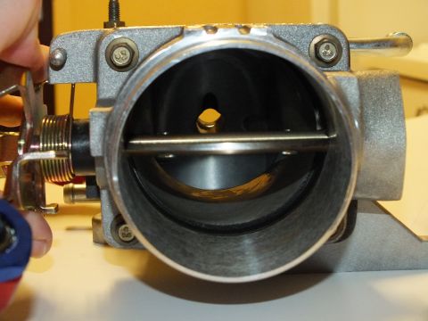 2003 Ford Crown Victoria - Front view into an aluminum throttle body bore with the throttle blade closed and a coil return spring visible