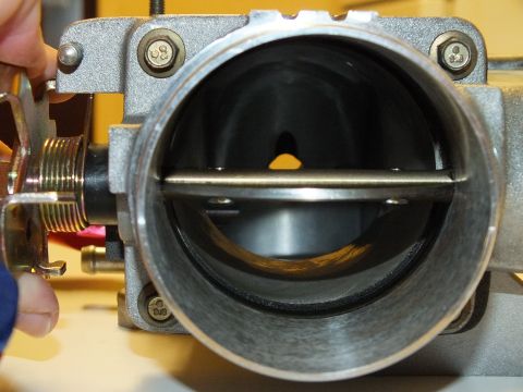 2003 Ford Crown Victoria - Inside an aluminum throttle body showing the level throttle blade, shaft and four corner mounting screws