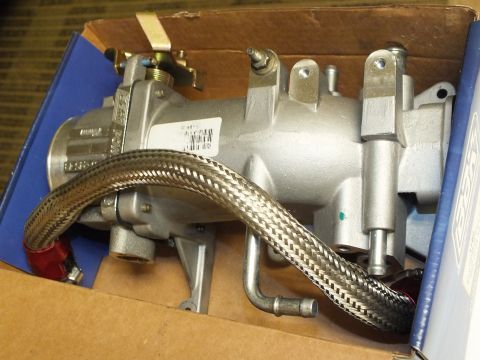 2003 Ford Crown Victoria - Top view of a cast aluminum intake with runners, throttle body and a draped braided hose in a box