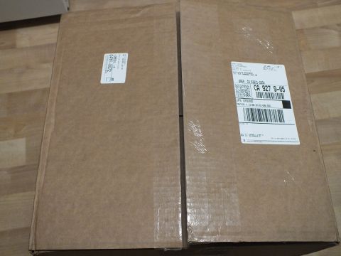2003 Ford Crown Victoria - Pair of taped kraft shipping boxes bearing printed address labels and barcodes on a laminate floor