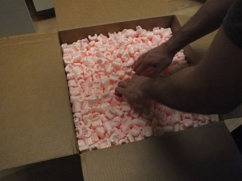 2003 Ford Crown Victoria - person reaches into a carton filled with pink foam packing peanuts to retrieve packed contents