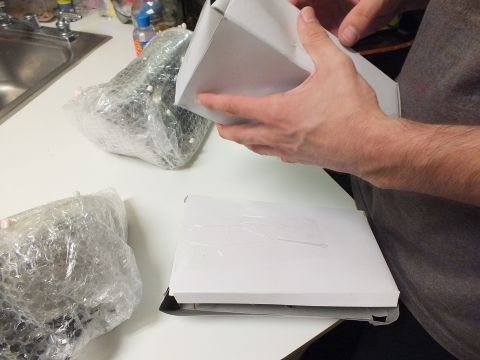 2003 Ford Crown Victoria - person opens a white box at a kitchen counter, with bubble-wrapped components and a sink nearby