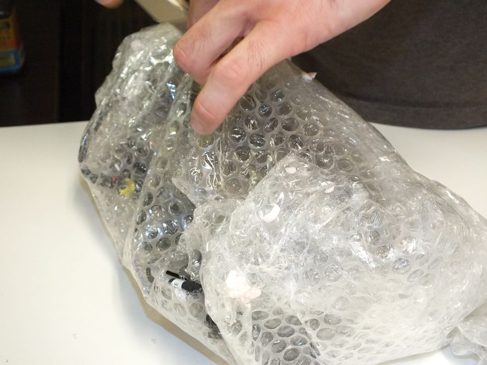 Hand peeling bubble wrap from a wired automotive component