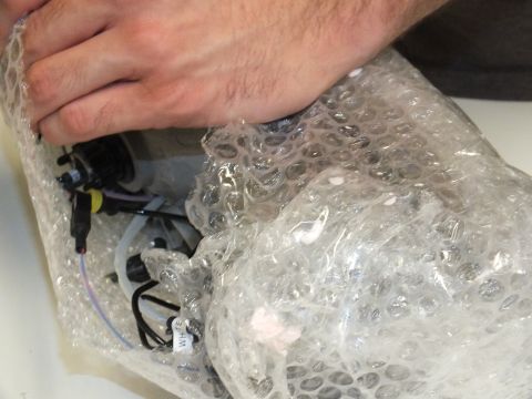 2003 Ford Crown Victoria - headlight housing with HID wiring and connectors emerges from bubble-wrap packaging.